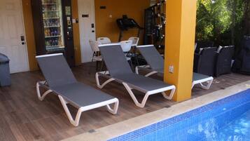 A pool area with lounge chairs and a water fountain.