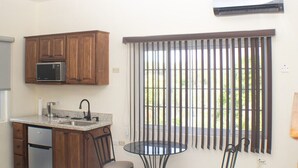 A kitchen with wooden cabinets, a microwave, a sink, and a ceiling fan. - The Vista Inn Studio #3 (Falmouth)
