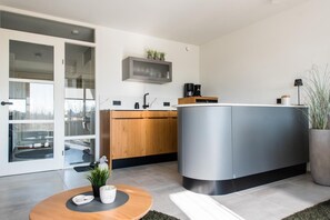 A modern kitchen with a built-in island, wooden cabinets, and a glass door leading to a balcony. - Fräulein Frieda 7 Ameland - great first floor apartment facing south - pets welcome (Ameland)