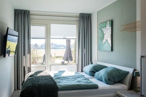 A bedroom with a bed, curtains, a star decoration, and a window with a view. - Fräulein Frieda 7 Ameland - great first floor apartment facing south - pets welcome (Ameland)