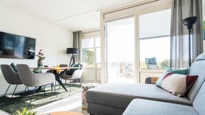 Una sala de estar moderna con un sofá, sillas, una mesa de centro y un televisor.