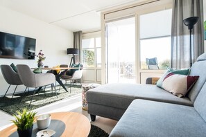 A modern living room with a sofa, chairs, a coffee table, and a TV. - Fräulein Frieda 7 Ameland - great first floor apartment facing south - pets welcome (Ameland)