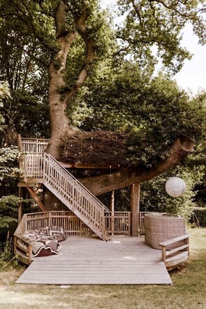 Une terrasse en bois avec un escalier menant Ă une cabane dans les arbres.