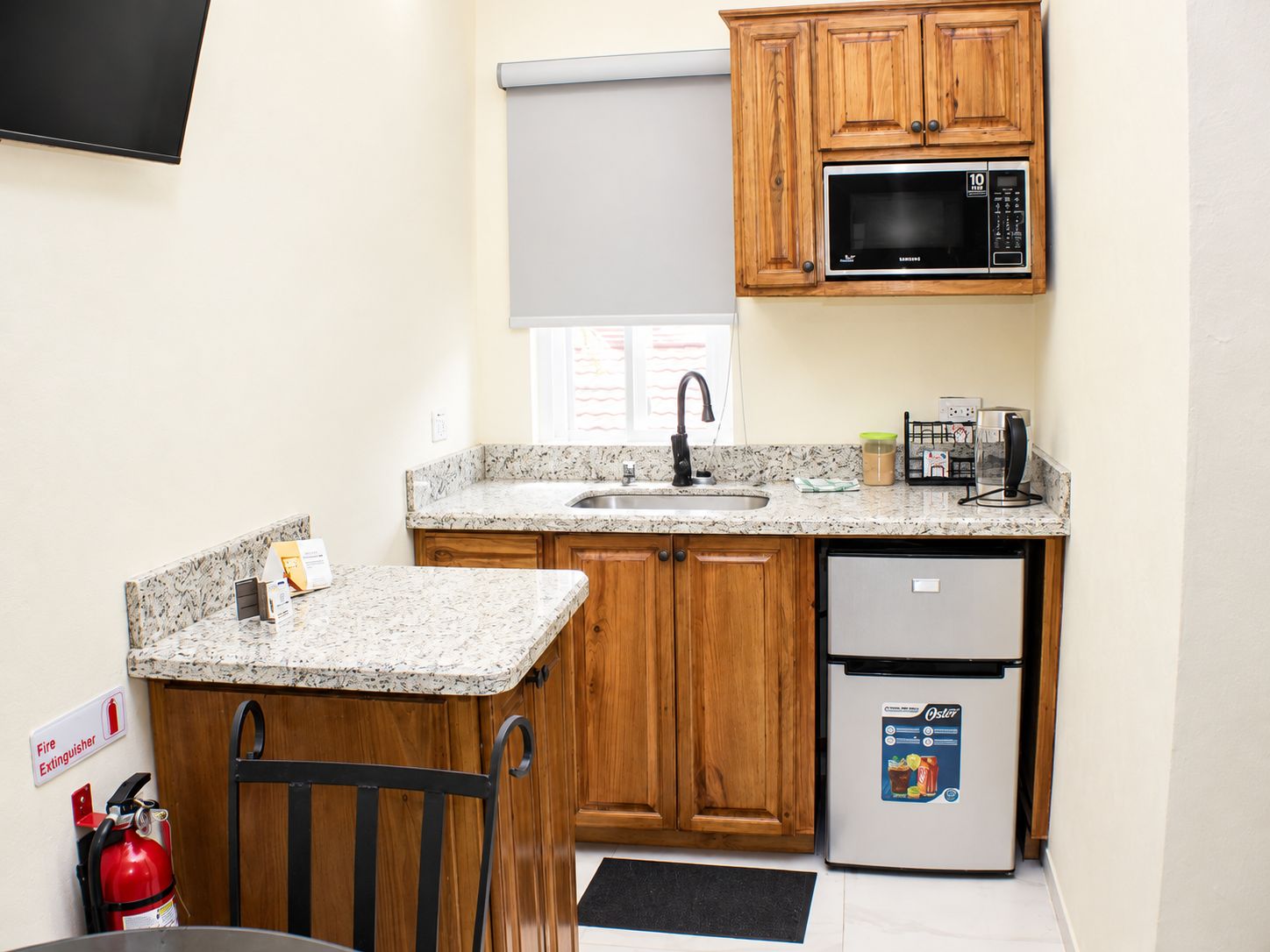 A compact kitchen with wooden cabinets, a microwave, a sink, and a refrigerator.