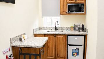 A compact kitchen with wooden cabinets, a microwave, a sink, and a refrigerator.
