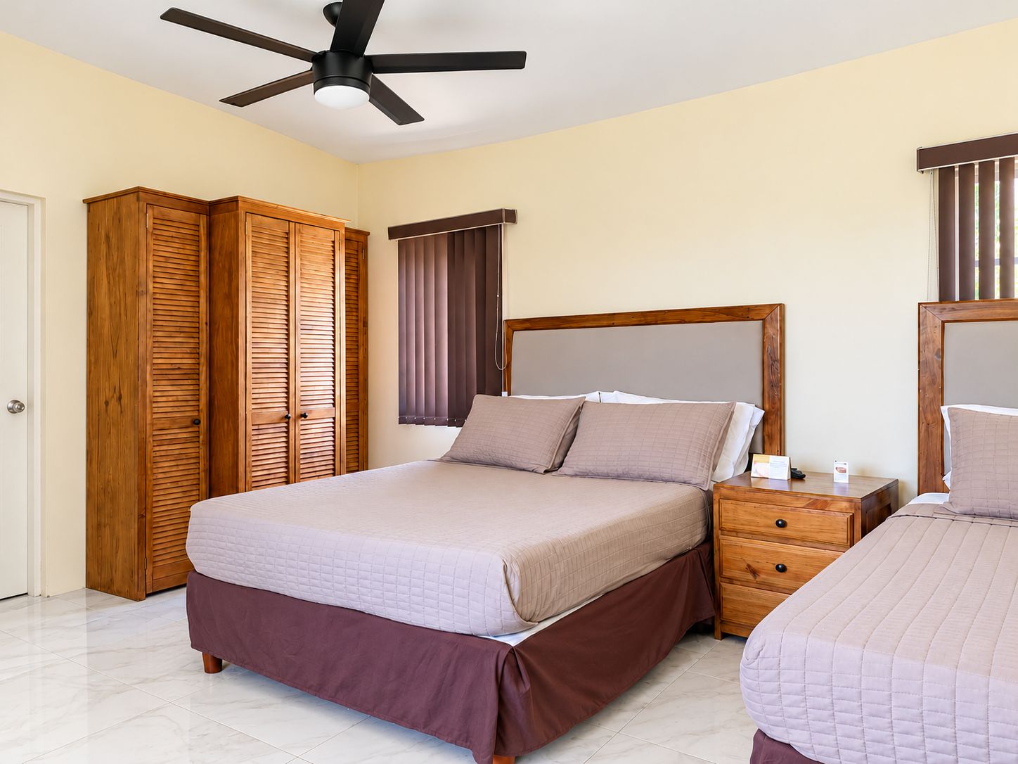 A bedroom with a bed, a nightstand, a wardrobe, and a ceiling fan.