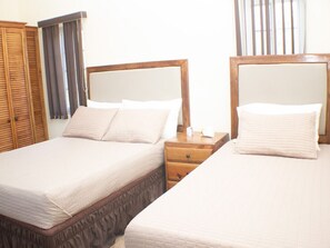 Due letti singoli con poggiatesta in legno, un comodino in legno e un armadio con specchio.
