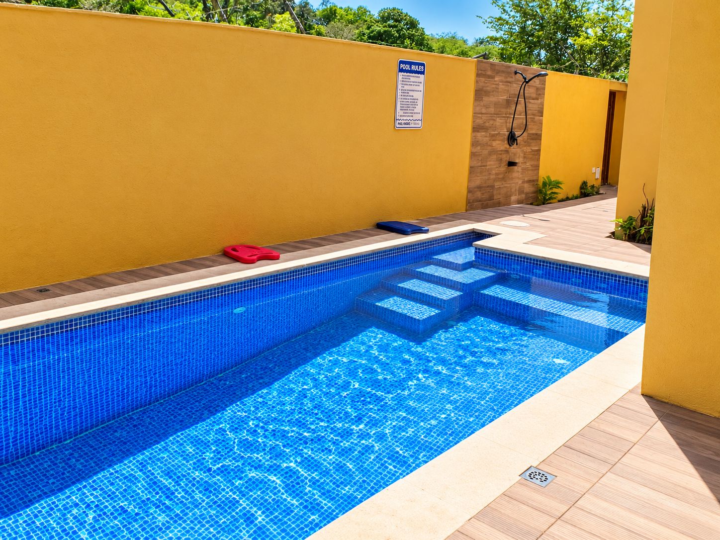 A swimming pool with a blue tiled interior, a yellow wall, and a 'POOL RULES' sign.