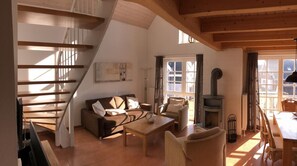 Ein Loft-Wohnzimmer mit Treppe, Kamin und Essbereich.