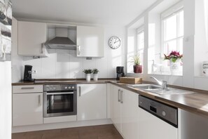 Eine moderne Küche mit weißen Schränken, Edelstahlgeräten und einer Holzausziehtafel.