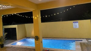 A pool area with two pools, string lights, a ceiling fan, and a pool rules sign. - The Vista Inn Suite #5 (Falmouth)
