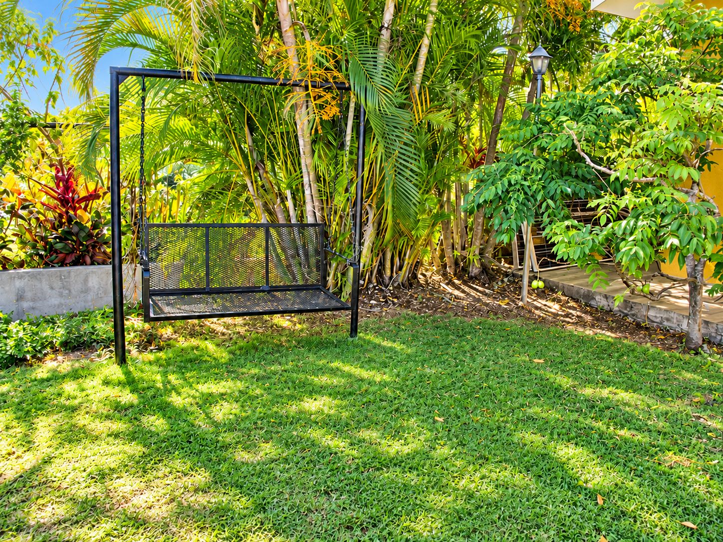 Relax in our tropical garden with lush greenery and a peaceful outdoor swing bench.