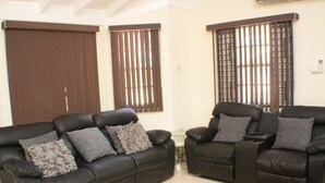 A living room with two black leather sofas, a patterned rug, and a large window with blinds. - The Vista Inn Suite #5 (Falmouth)