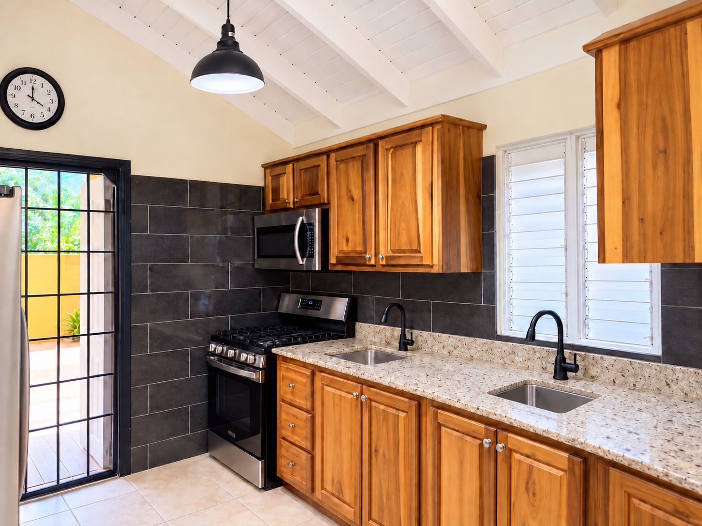 Kitchen with gas stove, microwave, wooden cabinetry, granite countertops, and two sinks.