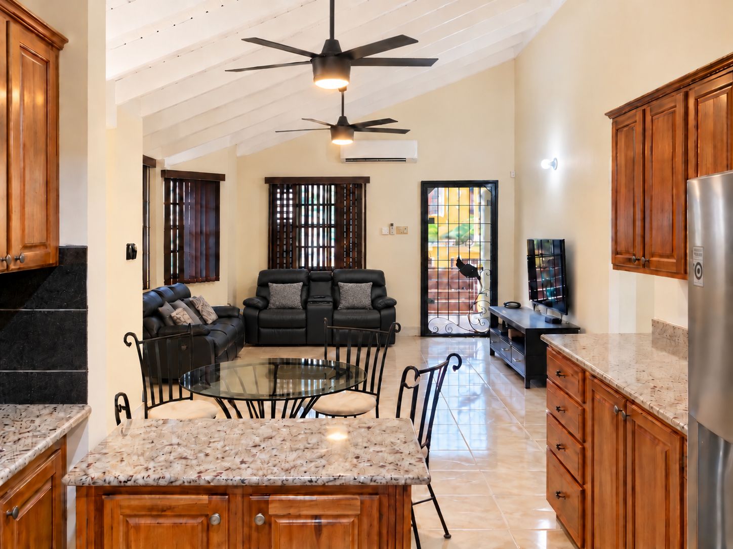A spacious kitchen with a dining area, wooden cabinets, and a ceiling fan.