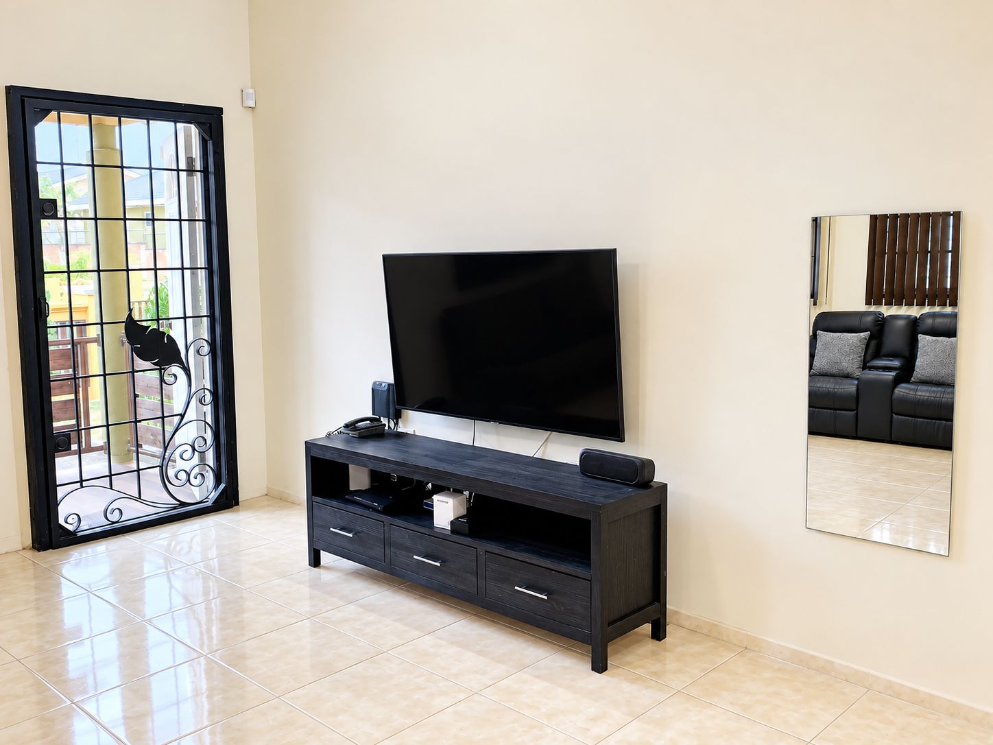 Een woonkamer met een televisie op een dressoir, een bank en een decoratieve spiegel.