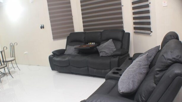 En stue med en sort sofa, et lille bord og en stol.
