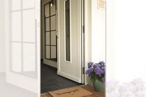Ein Flur mit Tür, Fußmatte und Topfpflanze.