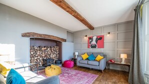 Een gezellige woonkamer met een open haard, een bank, een salontafel en een vloerkleed.