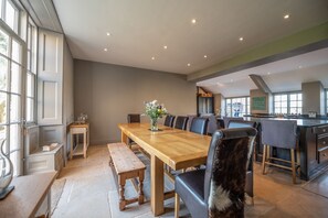 A spacious dining area with a long wooden table, multiple chairs, and a bench.