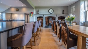 Een moderne keuken met een centraal eiland, een open haard en een eethoek met stoelen.