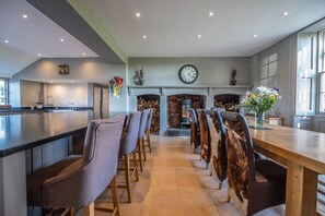 A modern kitchen with a central island, a fireplace, and a dining area with chairs.