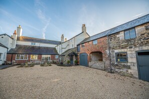 A courtyard with stone buildings, a gravel ground, and a small garden area.