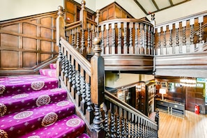 A multi-level wooden staircase with ornate balusters and a patterned carpet.