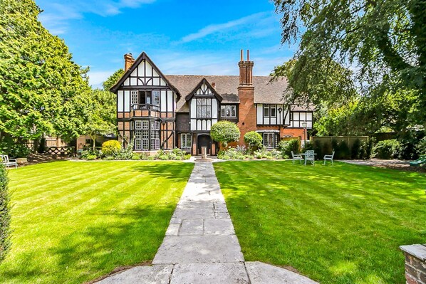 A Tudor-style house with a symmetrical facade, a central entrance, and a well-maintained lawn.