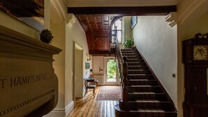 A grand staircase leading to a second floor, a fireplace with a plaque, and a clock on the wall. - Lakestone House - Five Bedroom Villa, Sleeps 10 (Windermere)