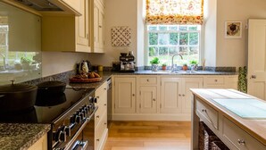 A kitchen with a stove, oven, and sink, with a window above the sink. - Lakestone House - Five Bedroom Villa, Sleeps 10 (Windermere)