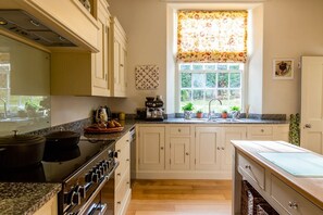 Eine Küche mit Herd, Backofen und Spüle, über der Spüle befindet sich ein Fenster.