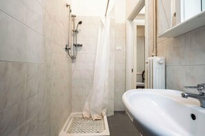 Et badeværelse med bruser, vask og toilet.