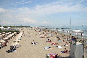 Uma praia com guarda-sóis, espreguiçadeiras e uma torre de vigilância.