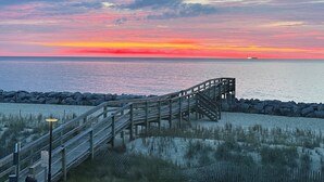 A wooden boardwalk leading to a beach with a sunset in the background.