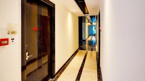 A hotel hallway with a marble floor, a black door with a handle, and a sign labeled 'G01' on the wall. - Suite Palette South Delhi Imperial Villa (New Delhi)