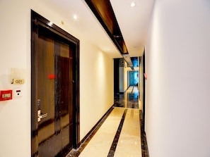 A hotel hallway with a marble floor, a black door with a handle, and a sign labeled 'G01' on the wall. - Suite Palette South Delhi Imperial Villa (New Delhi)