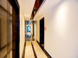 Un pasillo de hotel con piso reflectante, techo de madera y una puerta negra a la derecha.