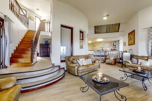Ein großzügiger Wohnbereich mit Treppe, zwei Sofas, einem Couchtisch und einer Küche im Hintergrund.