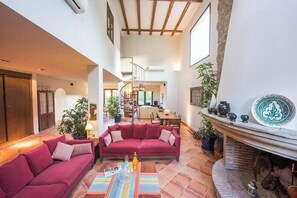 Ein großzügiger Wohnbereich mit einem roten Sofa, einem Kamin und einer Treppe, die in eine obere Etage führt.