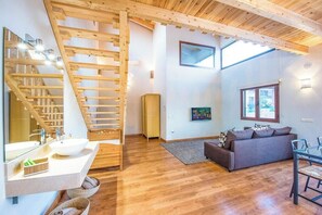 Ein modernes Interieur mit einer Holztreppe, einem großen Fenster, einer Couch und einem Essbereich.