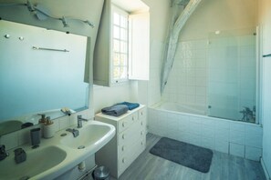 Une salle de bain équipée d’un lavabo, d’un miroir, d’un meuble-lavabo et d’un espace douche.