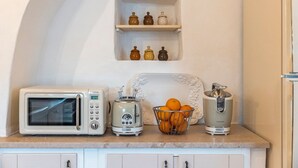 Una cocina con microondas, tostadora, extractor de zumo y un bol de naranjas sobre la encimera.
