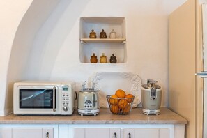 A kitchen with a microwave, toaster, juicer, and a bowl of oranges on the counter. - Masseria Zia Cocca - Five Bedroom Villa, Sleeps 10 (Martina Franca)