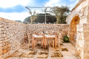 A stone-walled outdoor dining area with a table set for two, surrounded by stone flooring and a rustic ambiance. - Masseria Zia Cocca - Five Bedroom Villa, Sleeps 10 (Martina Franca)