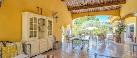 Un patio iluminado por el sol con comedor, un armario blanco y vistas al exterior.