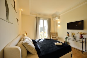 A bedroom with a bed, a chair, a TV, and a small table with plants.