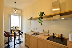 A modern kitchen with wooden cabinets, a black countertop, a sink, and a hanging plant.