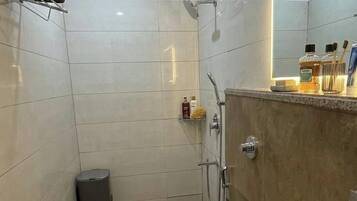 Un baño moderno con ducha, inodoro, lavabo y espejo con marco iluminado.
