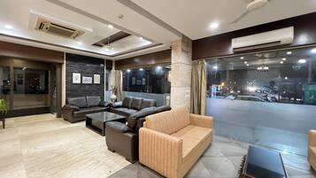 A modern living room with leather sofas, a glass coffee table, and a view of the street through large windows.